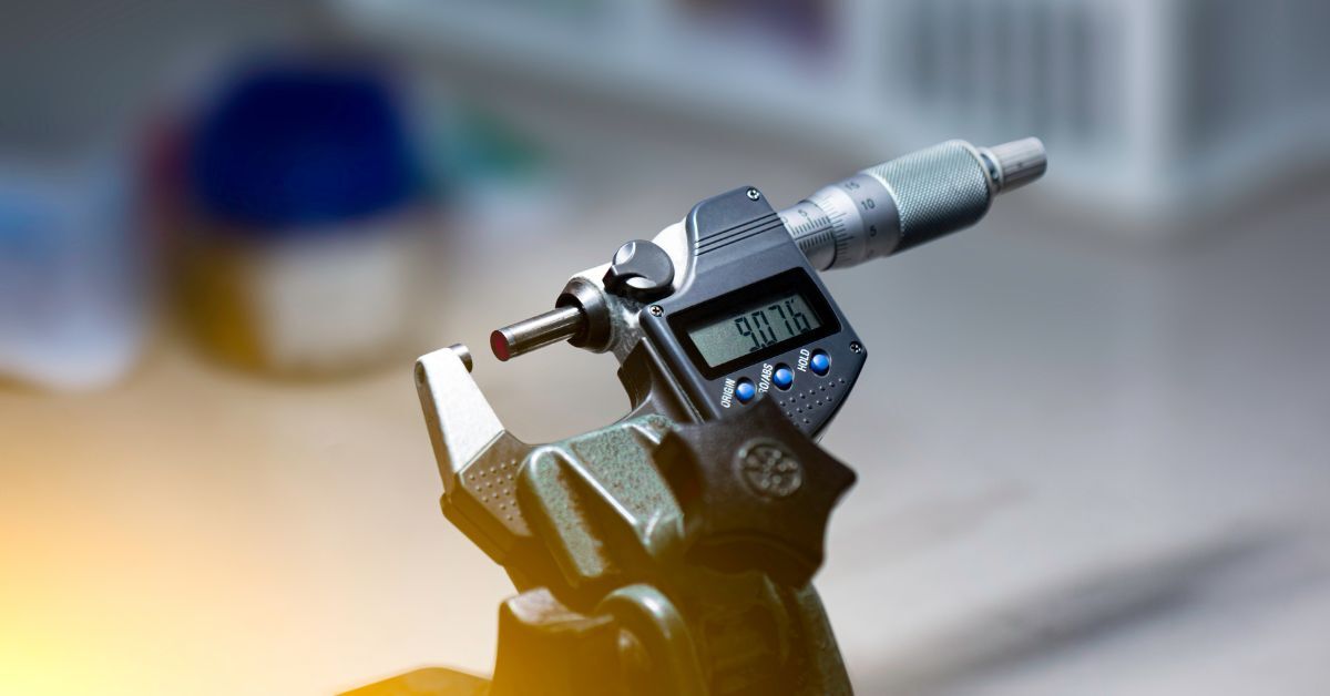 A small, black digital micrometer saved to its last measurement. The digital display reads 9.076.
