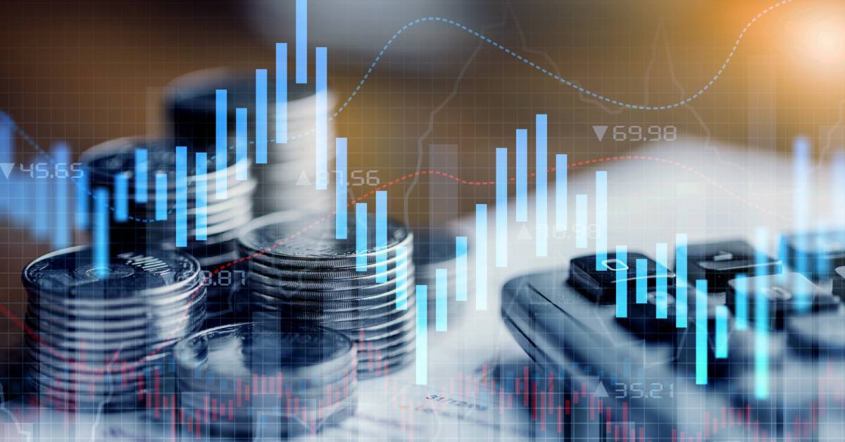 A graph of rising and falling data trends superimposed onto an image of a calculator and stacks of coins.