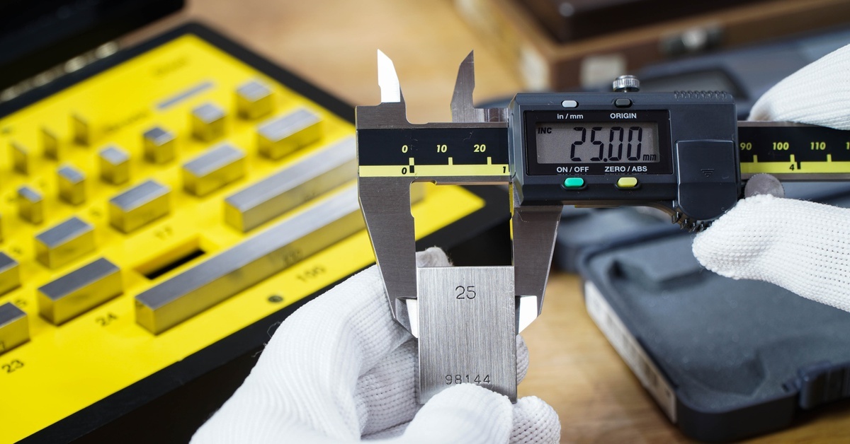 Someone measuring a 25mm block with a digital caliper to ensure accurate readings. The display reads 