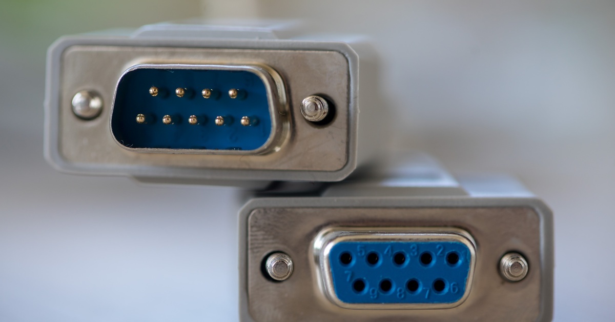 Two ends of a gray RS232 connection cord. The male connection rests on top of the female connection.