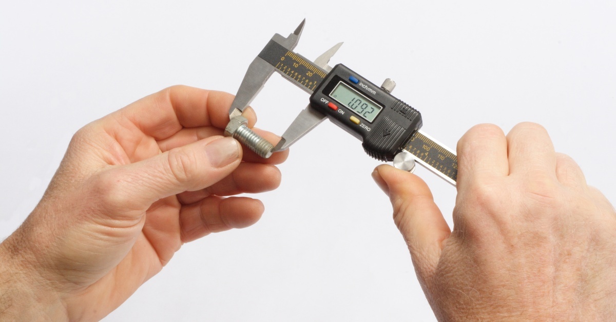 A person holds a digital caliper and measures the length of a screw. The caliper reads "1.092."